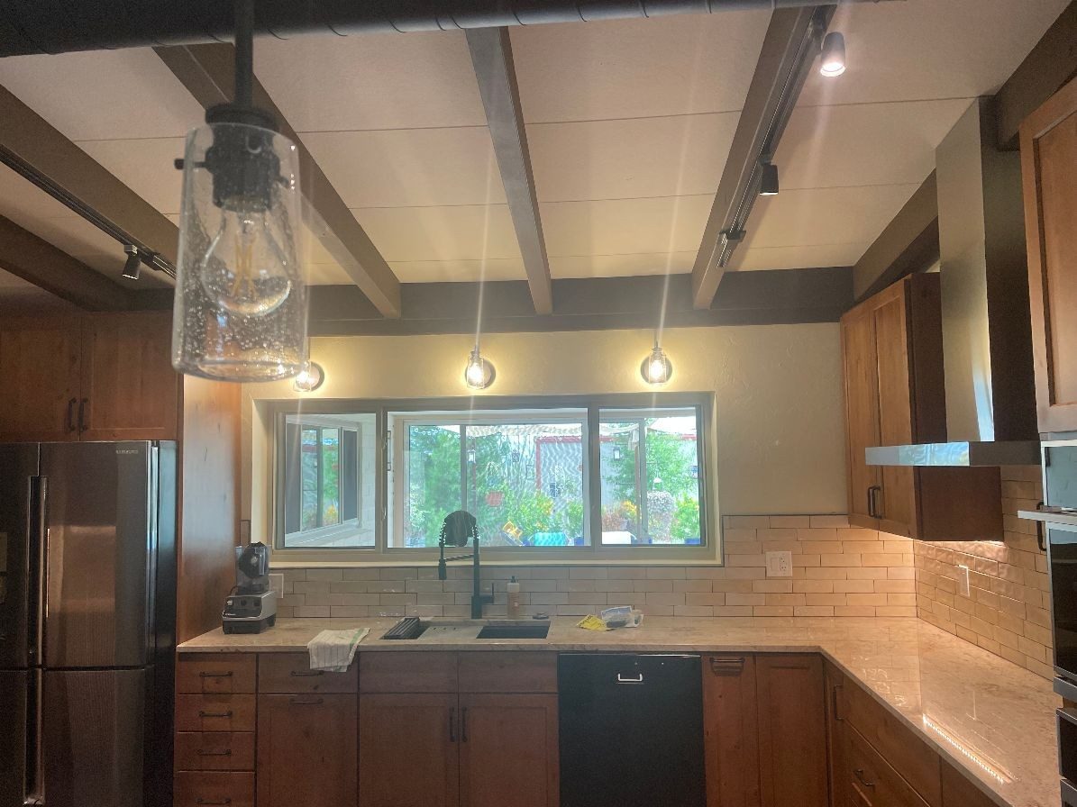 Remodeled kitchen with wood cabinetry and tile backsplash by STM Development
